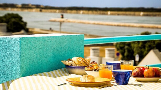 A balcony with a table set for breakfast, overlooking a river.