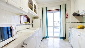 A kitchen with white cabinets, a microwave, a sink, and a stove.