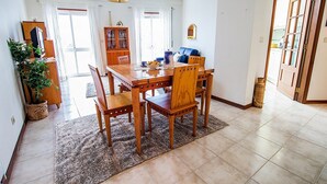A dining area with a wooden table and chairs, a cabinet with glass doors, and a potted plant.