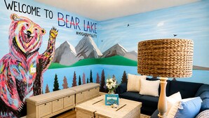 Une pièce décorée d’une fresque représentant un ours, avec un canapé, une table basse et une lampe.