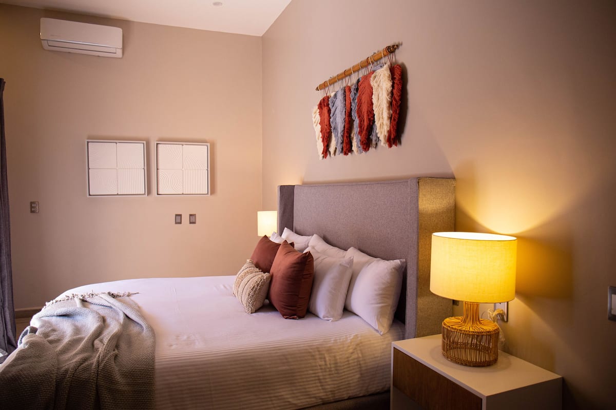 A neatly made bed with pillows, a bedside lamp, and a wall-mounted artwork.