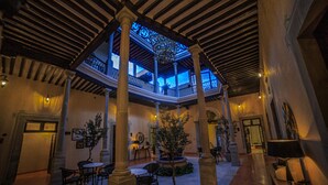 A spacious indoor area with a central open space supported by columns, surrounded by seating and potted plants. - Hotel Boutique Corazón Mexicano (Guanajuato)