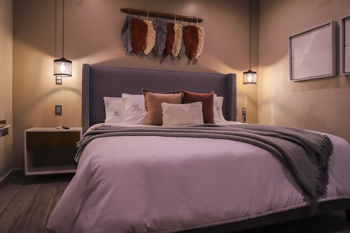A modern bedroom with a large bed, a nightstand, and two wall-mounted lamps.