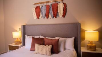 A neatly made bed with a grey headboard, white and brown pillows, and a decorative wall hanging above.