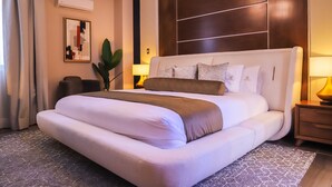 A modern hotel room with a large bed, a bedside table, a lamp, and a wall-mounted air conditioner. - Hotel Boutique Corazón Mexicano (Guanajuato)
