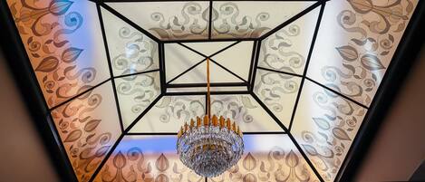 Een plafond met een geometrisch patroon en een kroonluchter.