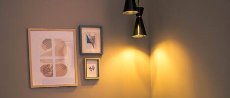 A modern room with a grey chair, a small round table, and two framed artworks on the wall.