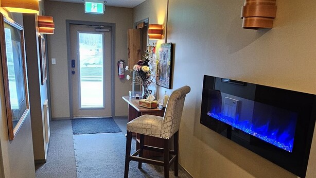 A hotel lobby with a reception desk, a seating area, a wall-mounted TV, and a fish tank.