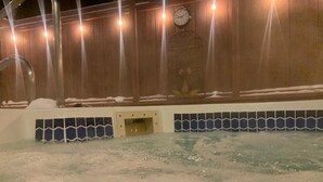 A hot tub area with a wooden wall, a clock, and a tiled border.