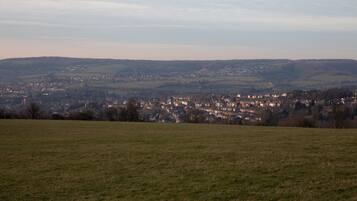 A panoramic view of a town with a large open field in the foreground and a densely built town in the background.