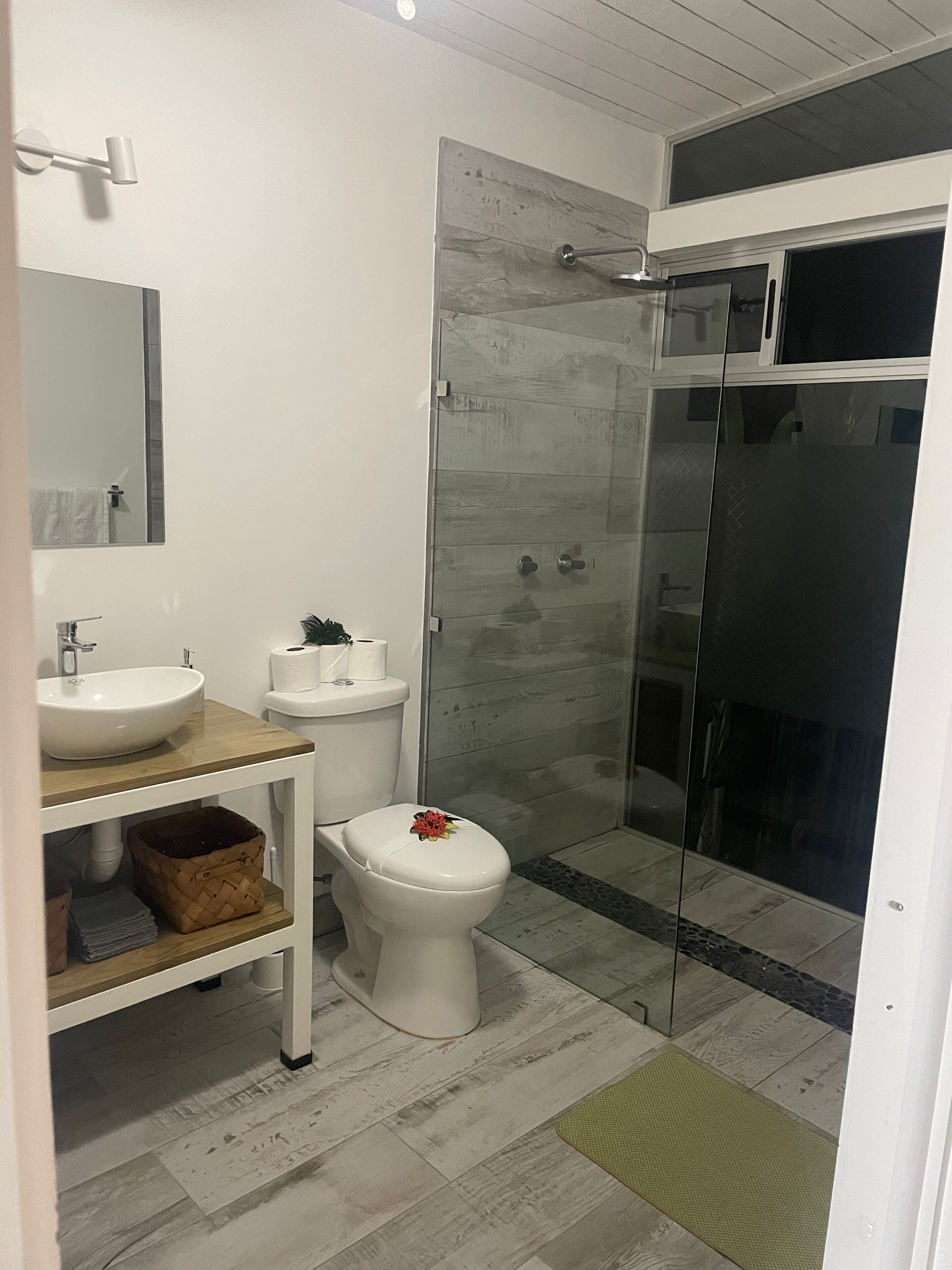 A modern bathroom with a white sink, toilet, and shower.