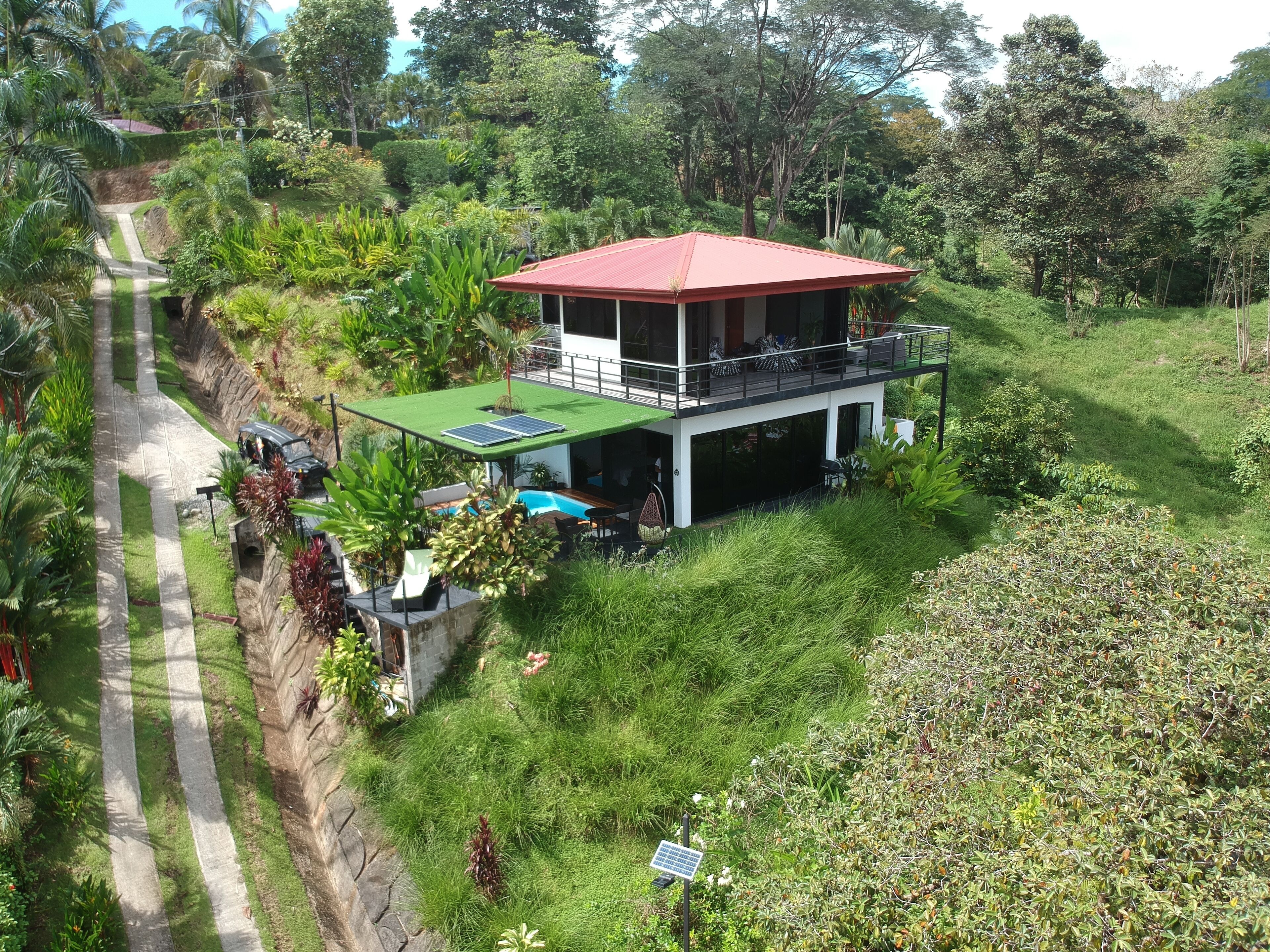 A two-story house with a red roof, a balcony, and a swimming pool.