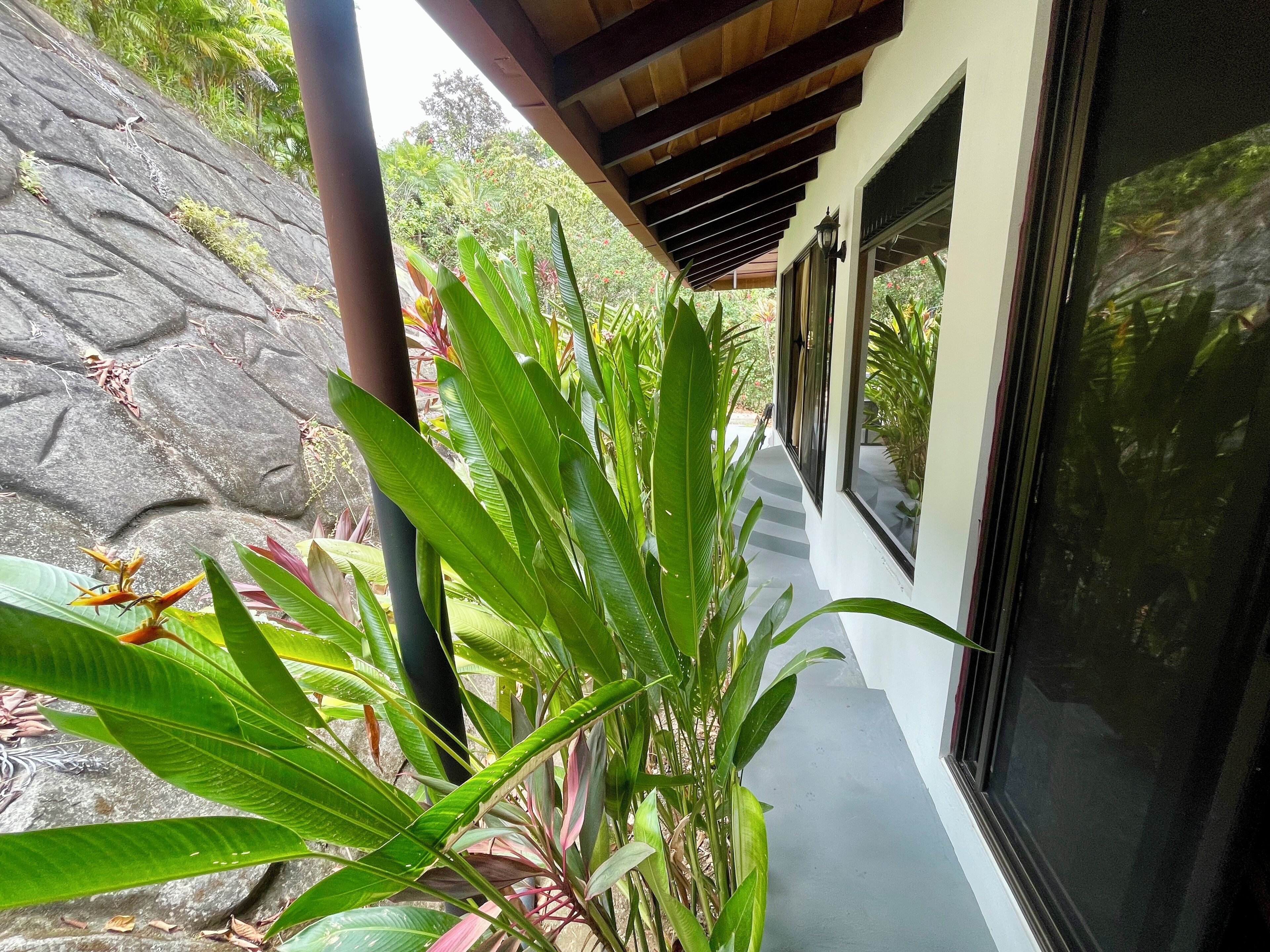 A covered outdoor corridor with a stone wall on one side and a glass door on the other.