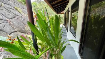 A covered outdoor corridor with a stone wall on one side and a glass door on the other.