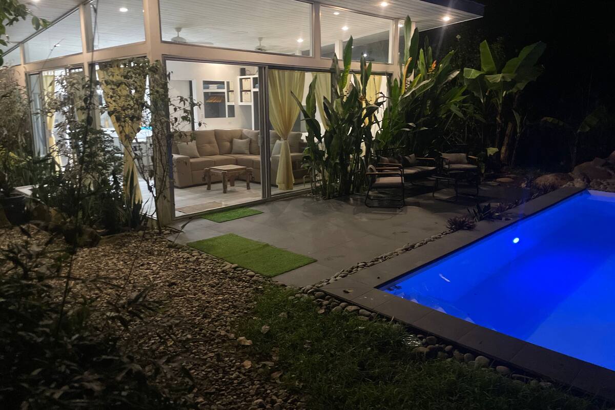 Uma casa moderna com fachada de vidro, piscina e móveis de exterior.