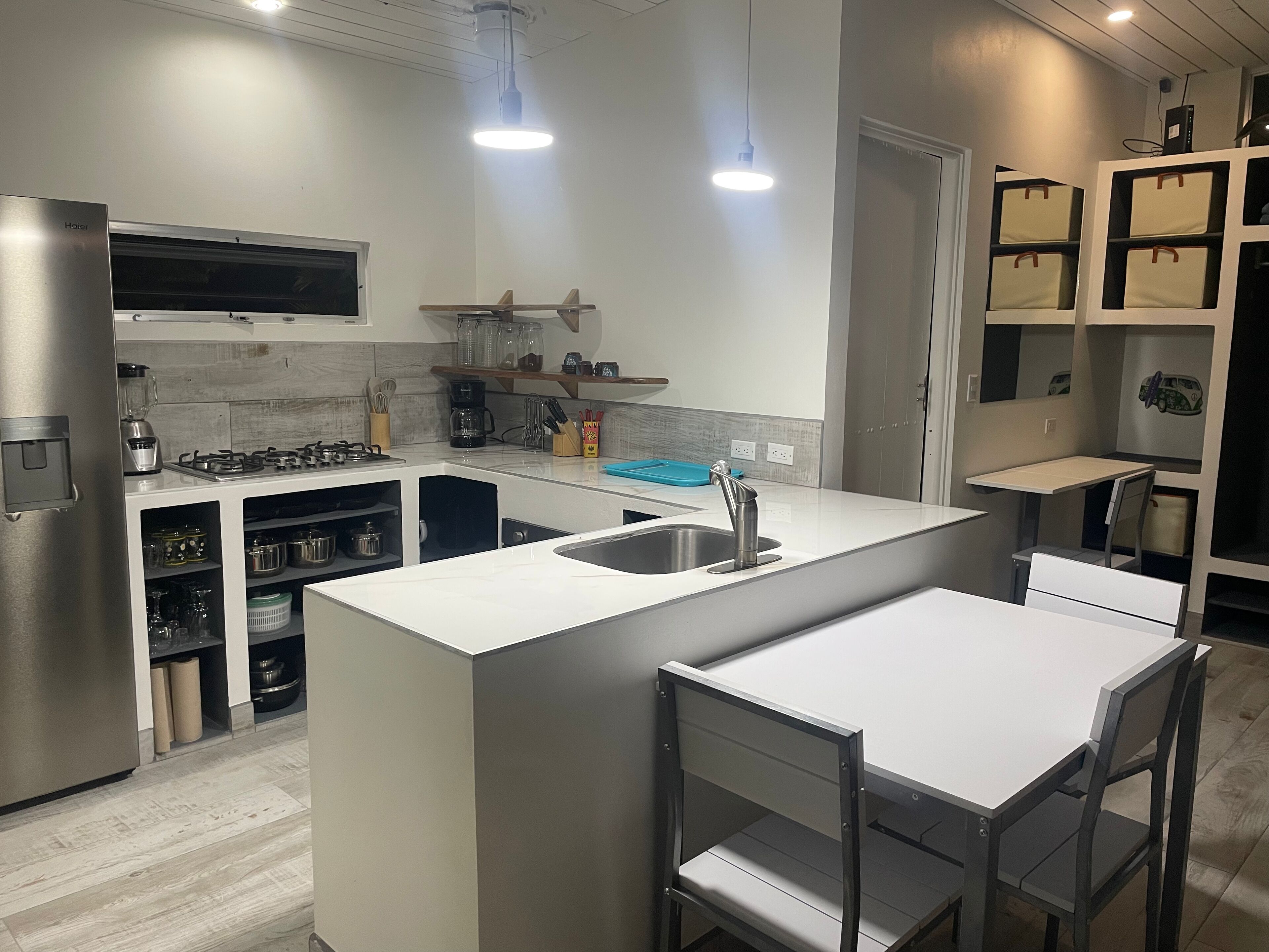 A modern kitchen with a central island, built-in appliances, and a dining area with a table and chairs.