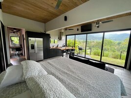 Un dormitorio con una cama grande, una kitchenette y vistas a un paisaje exuberante.