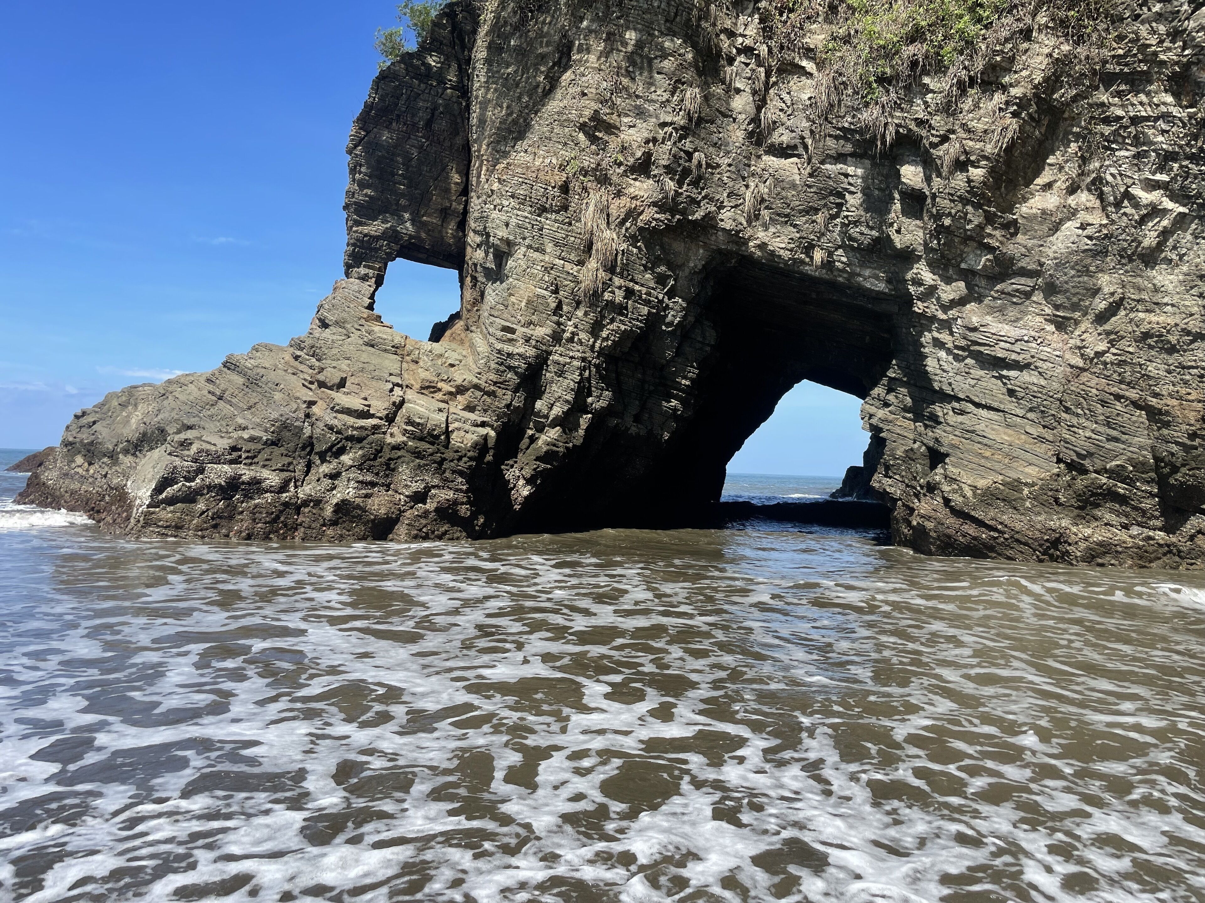 Formación rocosa natural con un arco grande sobre el agua.