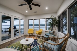 Enjoy a serene view of the lake from this room's large window, featuring a comfortable seating area and a potted plant.