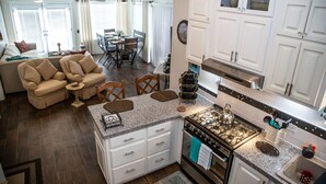 Una cocina moderna con armarios blancos, estufa a gas y comedor con mesa y sillas.
