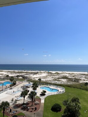 A beach resort with multiple swimming pools, a sandy beach, and a clear view of the ocean.
