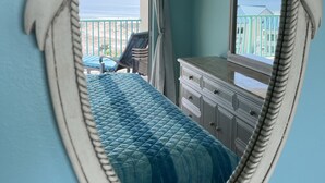 Una habitación con cama, cómoda y vista al océano a través de una ventana.