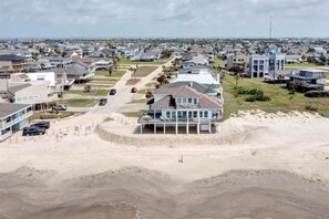 Een woongebied aan de kust met huizen, een strand en een groot gebouw met een balkon dat uitkijkt over het strand.