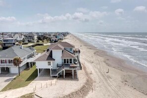 Een strandhuis met meerdere woningen, een zandstrand en de oceaan.