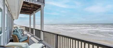 Un balcón con sillones de mimbre y vista a la playa.