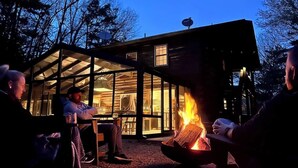 Un chalet confortable doté d’une véranda en verre, d’un foyer et d’un espace repas.
