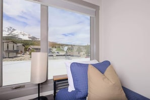 A room with a large window offering a view of a snowy mountain and a parking area.