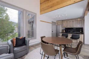 A modern kitchen with wooden cabinets, a central island, and a dining area with a round table and chairs. - 2 Bedroom With Loft Located in Big Sky Resort Area (Big Sky)