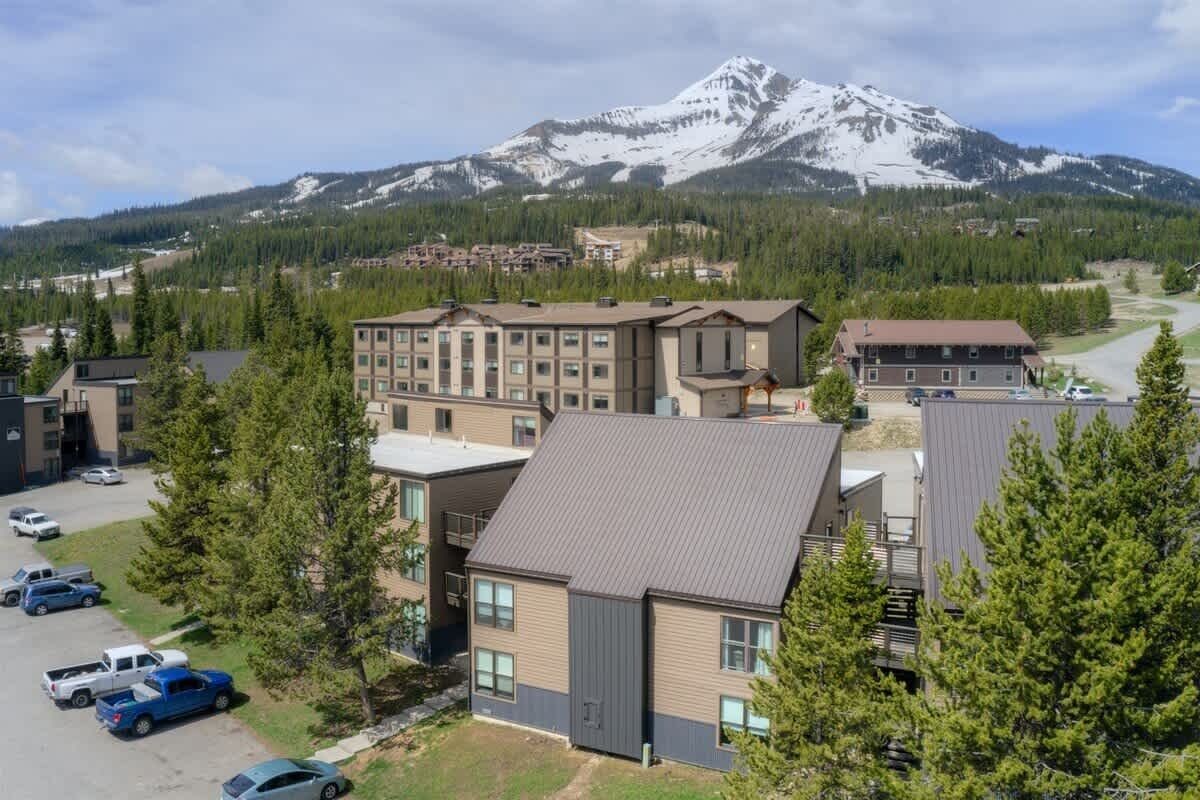 A hotel with multiple buildings, a parking lot, and a mountain in the background.