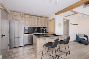 A modern kitchen with stainless steel appliances, a central island with bar stools, and light wooden cabinets. - 2 Bedroom With Loft Located in Big Sky Resort Area (Big Sky)