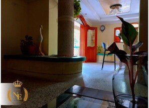 A lobby with a glass coffee table, a potted plant, and a decorative vase. - Hotel New Hope (Barranquilla)