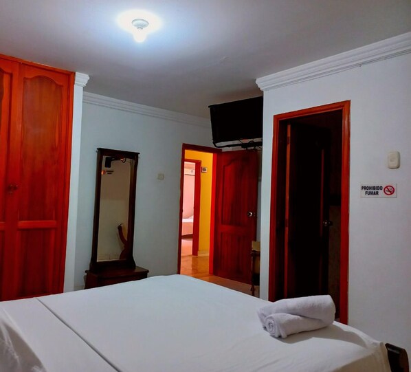 A hotel room with a bed, a mirror, and red doors. - Hotel New Hope (Barranquilla)