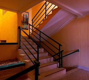 A staircase with black railings and a handrail, leading to a landing with a framed picture. - Hotel New Hope (Barranquilla)