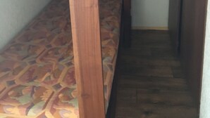 Una cama litera con colchón estampado, cabecera de madera y un pequeño cajón.