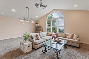 Relax in this inviting living room with a high ceiling, sofa, and large window.