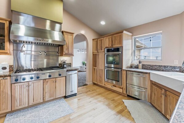 Enjoy cooking in this well-equipped kitchen with a stainless steel range hood, double ovens, and dishwasher.