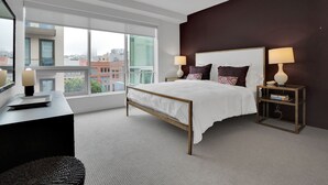Ein modernes Hotelzimmer mit einem großen Bett, Nachttischlampen, einem Schreibtisch und Blick auf die Stadt.