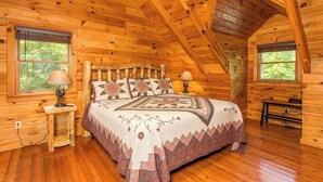 A wooden cabin bedroom with a bed, two windows, and a sloped ceiling. - Pigeon Forge Cabin /Game Room/Dog Friendly/Hot Tub (Pigeon Forge)