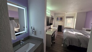 A hotel room with a bathroom, a desk, a bed, and a window. - The Aqua Pacific Hotel (Santa Cruz)