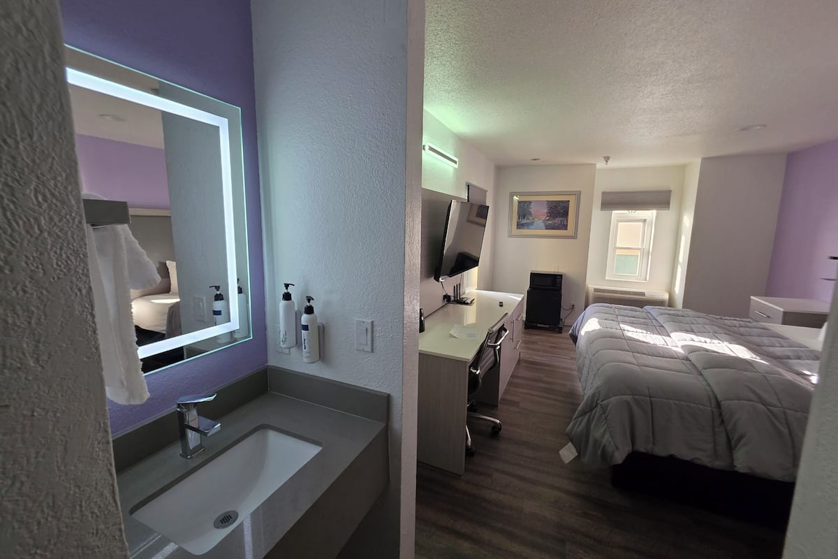Une chambre d’hôtel avec une salle de bain, un bureau, un lit et une fenêtre.