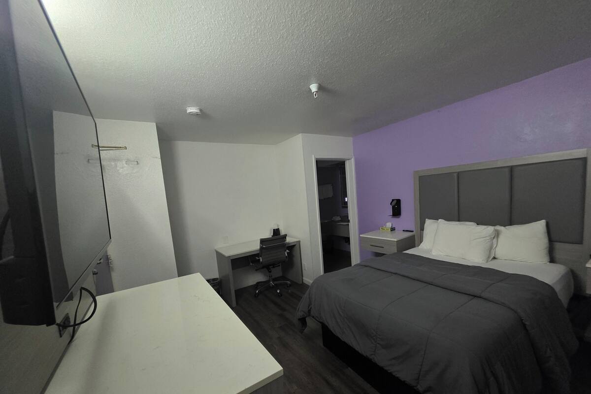 Une chambre d’hôtel comprenant un lit, un bureau, une chaise, une table de chevet et un miroir.