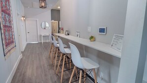 Cozinha moderna com bancada branca, banquetas e luminária pendente.