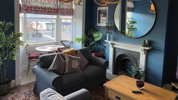 A cozy living room with a fireplace, a round mirror, and a chandelier. - Great for exploring North Yorkshire (Easingwold)
