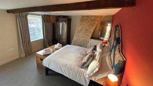 A hotel room with a bed, a wooden headboard, a mirror, a dresser, and a window with curtains. - Great for exploring North Yorkshire (Easingwold)