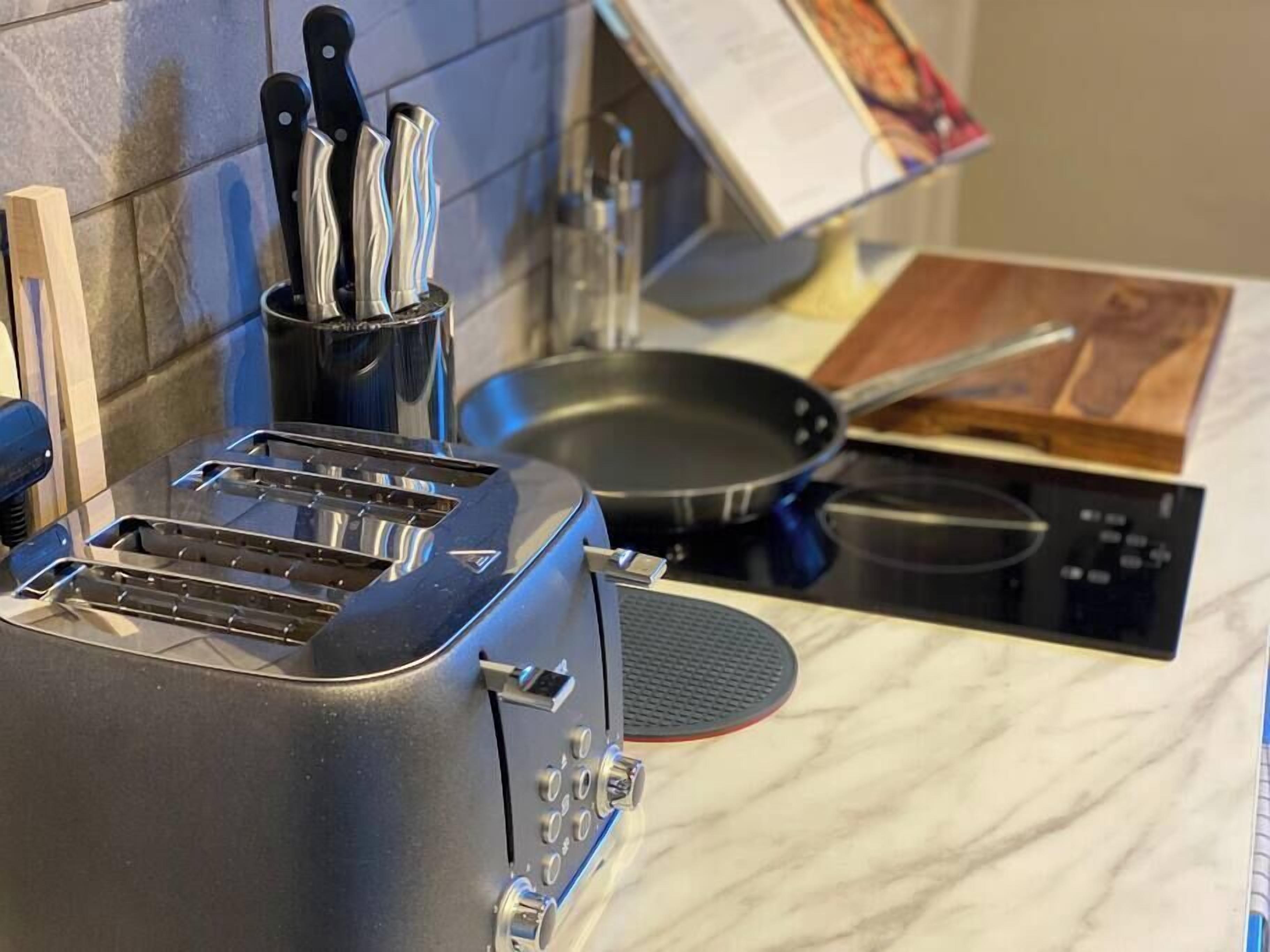 A kitchen with a toaster, a frying pan, and a cutting board on the counter.