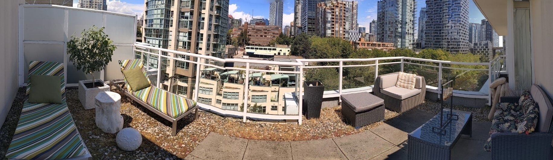 Un balcon avec des sièges d’extérieur, une vue sur le paysage urbain et un bâtiment à la façade incurvée.